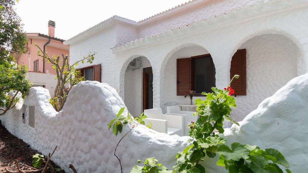 a white building with white chairs in front of it at Welcomely - Sandy House in Putzu Idu