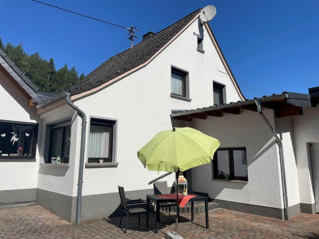 une table avec un parasol vert devant une maison dans l'établissement Apartment Kleeblatt by Interhome, à Breidscheid