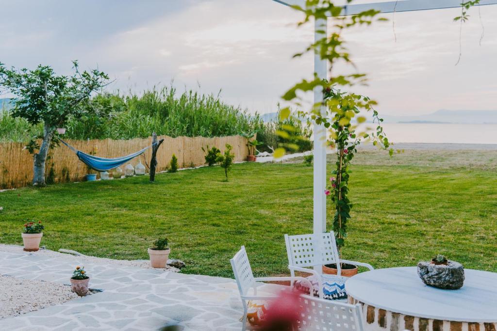 a table and chairs and a hammock in a yard at House by the Sea in Lefkímmi