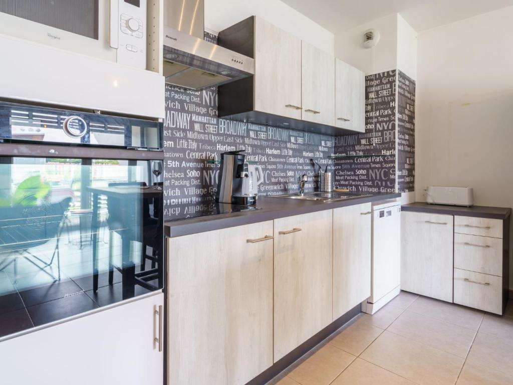 a kitchen with white cabinets and a brick wall at Apartment Rivadour 2 by Interhome in Bayonne
