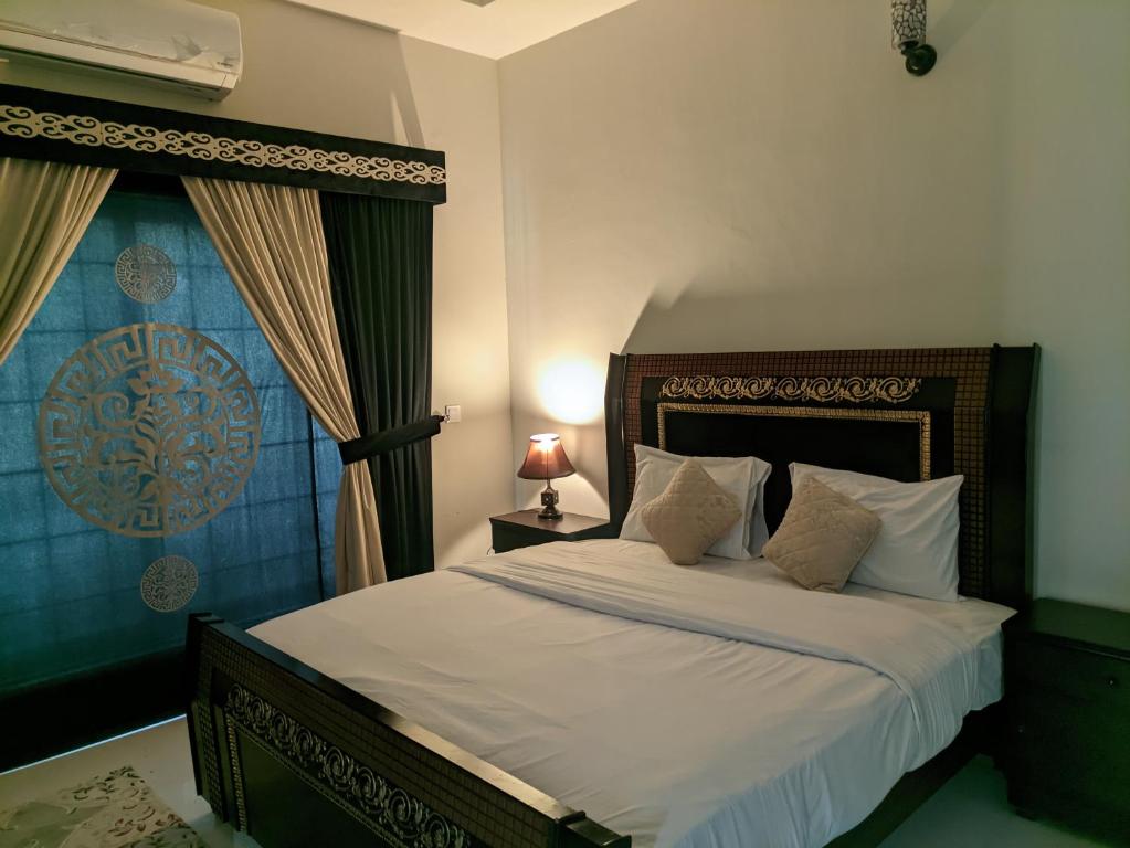 um quarto com uma cama com lençóis brancos e uma janela em White Palace Guesthouse em Islamabad