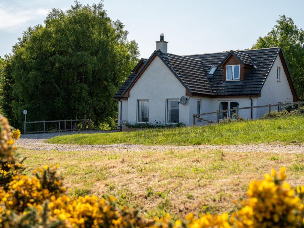 una casa blanca con un techo negro en un campo en Holiday Home Shedfield by Interhome en Drumnadrochit