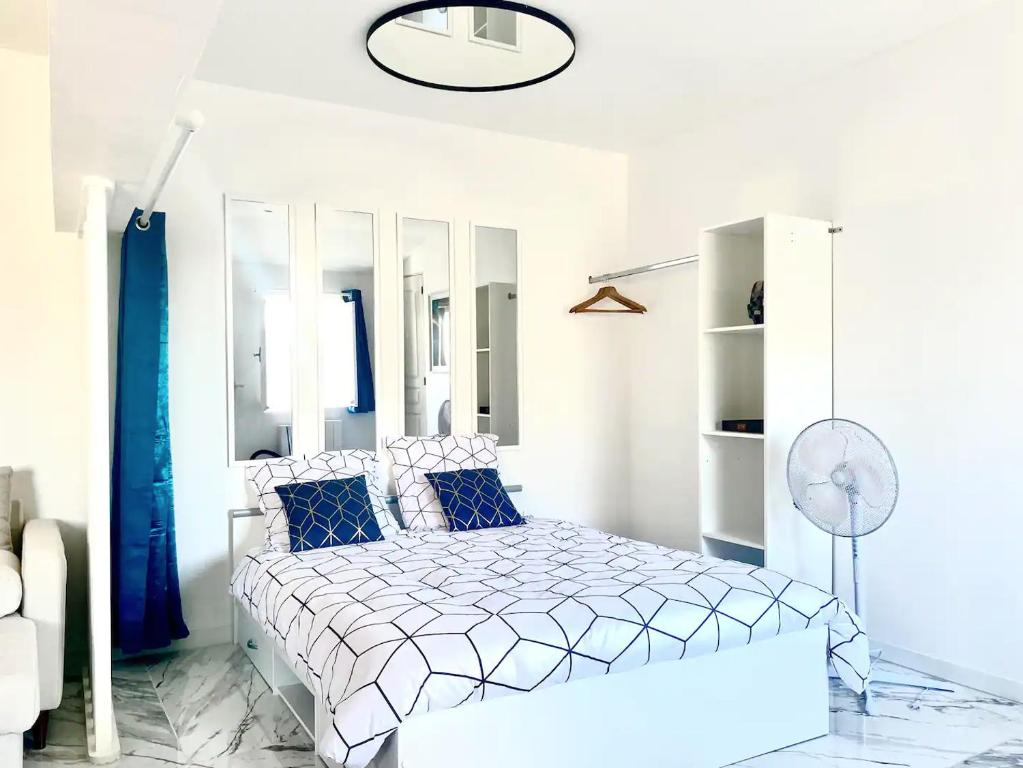 een witte slaapkamer met een bed met blauwe kussens bij Appartement climatisé à Béziers avec Jacuzzi & Rétroprojecteur - Le Palais des Glaces in Béziers