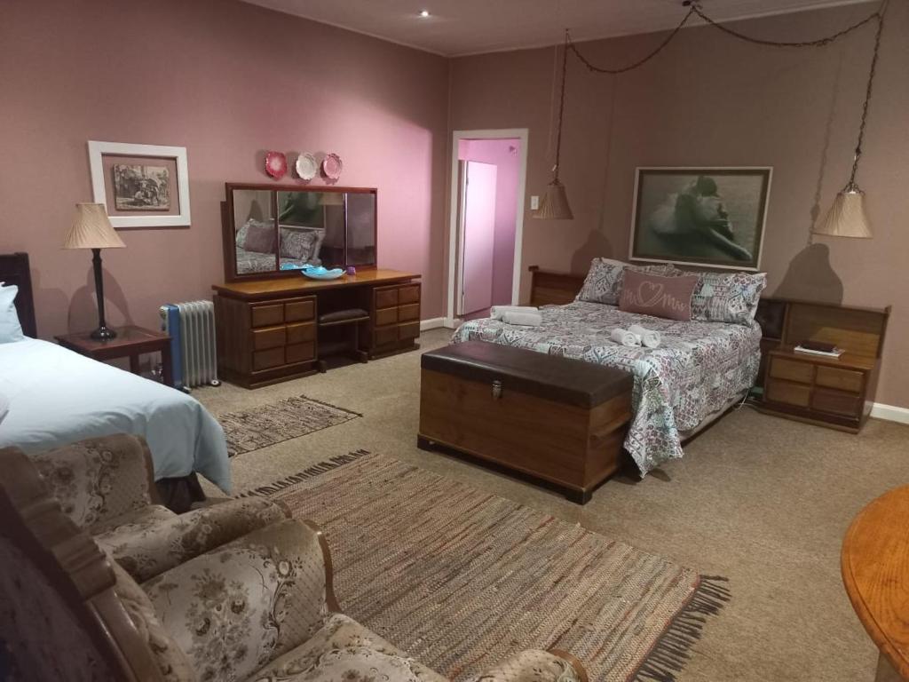 a bedroom with a bed and a couch and a table at Silver Mist Guest House, Country Inn and Herberg in Kaapsehoop