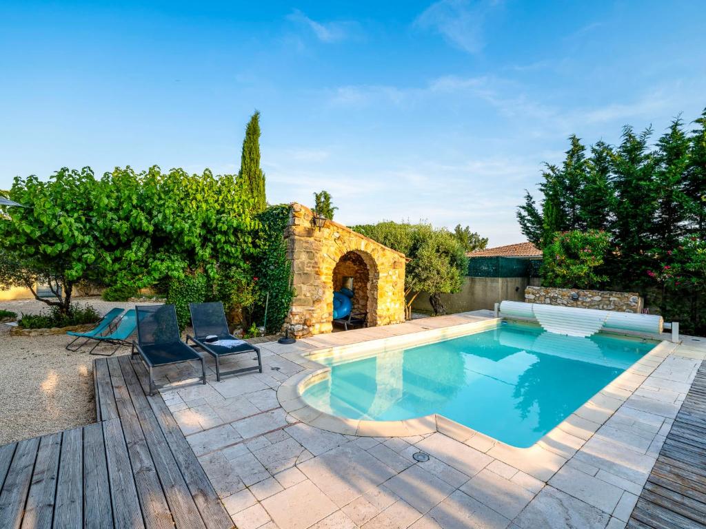 a swimming pool in a yard with chairs and a house at Holiday Home Le Mas d&#39;Adélaïs by Interhome in Baron