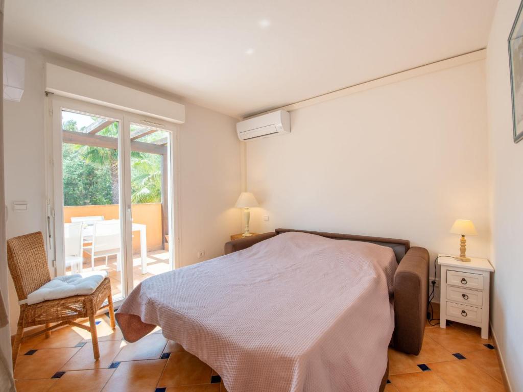a bedroom with a bed and a chair and a window at Apartment Les Lavandiers by Interhome in Cavalaire-sur-Mer