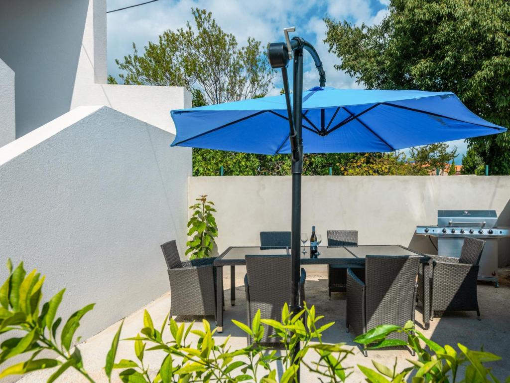 une table avec un parasol bleu et des chaises dans l'établissement Apartment Bura by Interhome, à Krnica