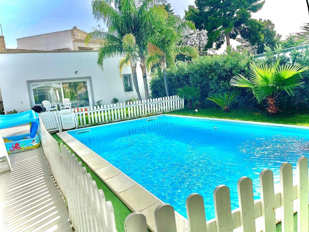 a swimming pool next to a white fence at Angolo paradiso in Castelvetrano Selinunte