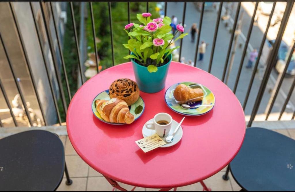 Apartment NAPOLI MARADONA في نابولي: طاولة وردية مع المعجنات و مزهرية مع الزهور