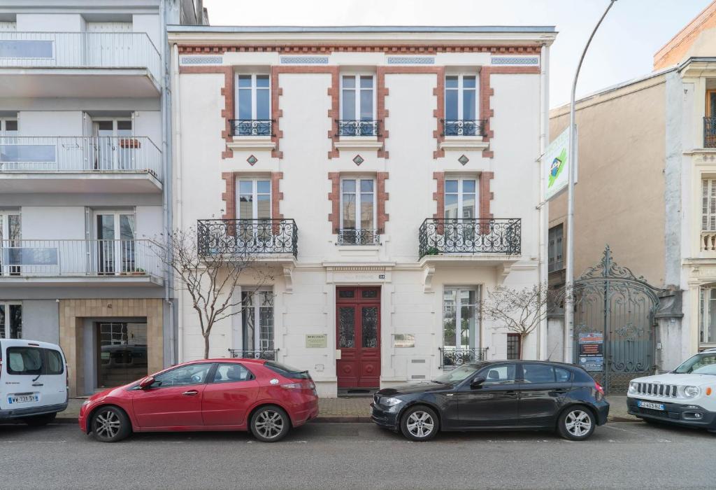 due auto parcheggiate di fronte a un edificio di Résidence Bains Callou située face aux thermes a Vichy
