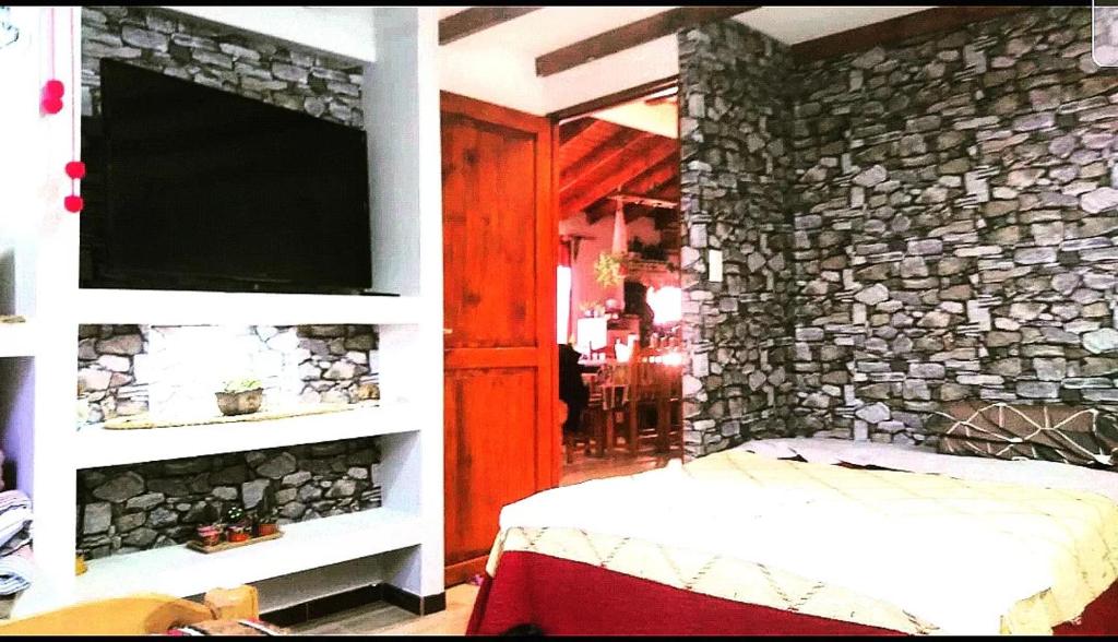 a bedroom with a stone wall with a tv at Cabaña Onty in El Calafate
