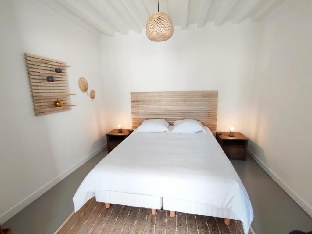 ein Schlafzimmer mit einem weißen Bett und zwei Nachttischen in der Unterkunft Charmant studio en centre-ville. in Saint-Pierre-sur-Dives