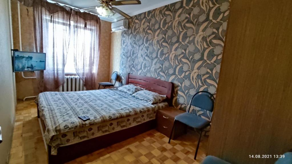 a bedroom with a bed and a chair and a tv at Apartment Tiraspol Center in Tiraspol