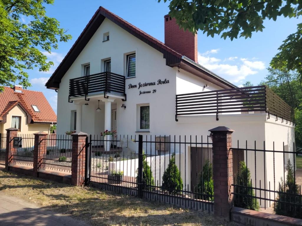 a white house with a black fence at Dom Jeziorna Perla in Ośno Lubuskie