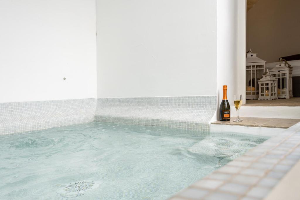 a bottle of wine sitting next to a swimming pool at Palazzo Rapanà - Luxury Apt with hydromassage pool in Ostuni