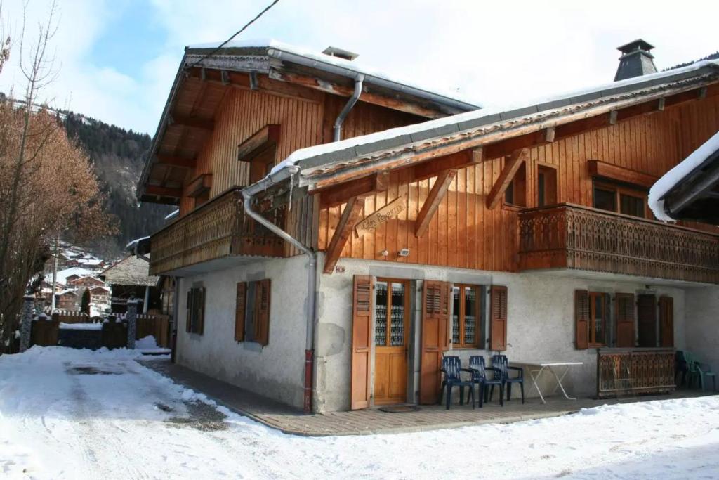 uma casa de madeira com uma mesa e cadeiras na neve em Chalet Poupette em Morzine