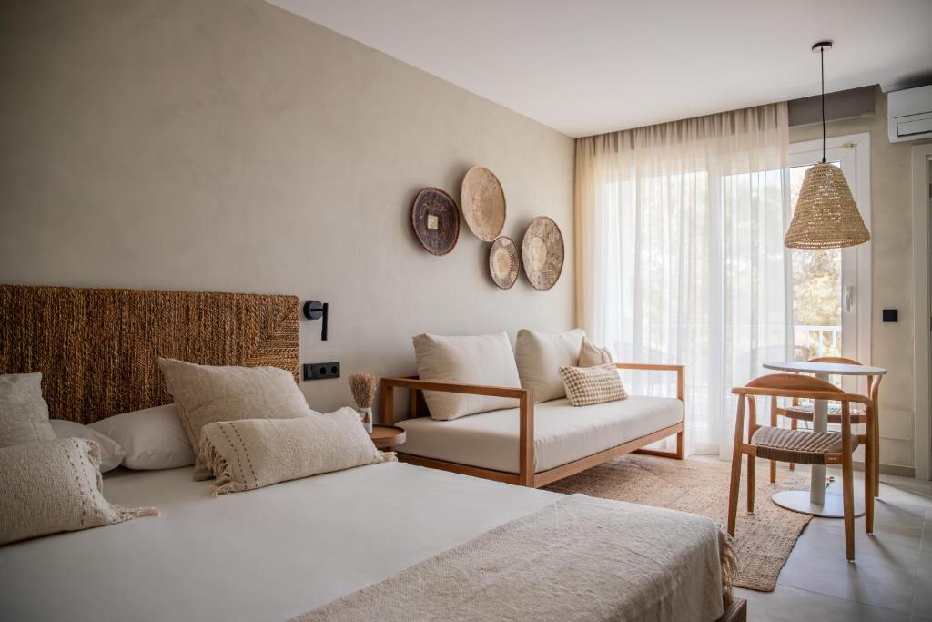 - une chambre avec un lit, un canapé et une chaise dans l'établissement Boho Suites Formentera, à Es Pujols
