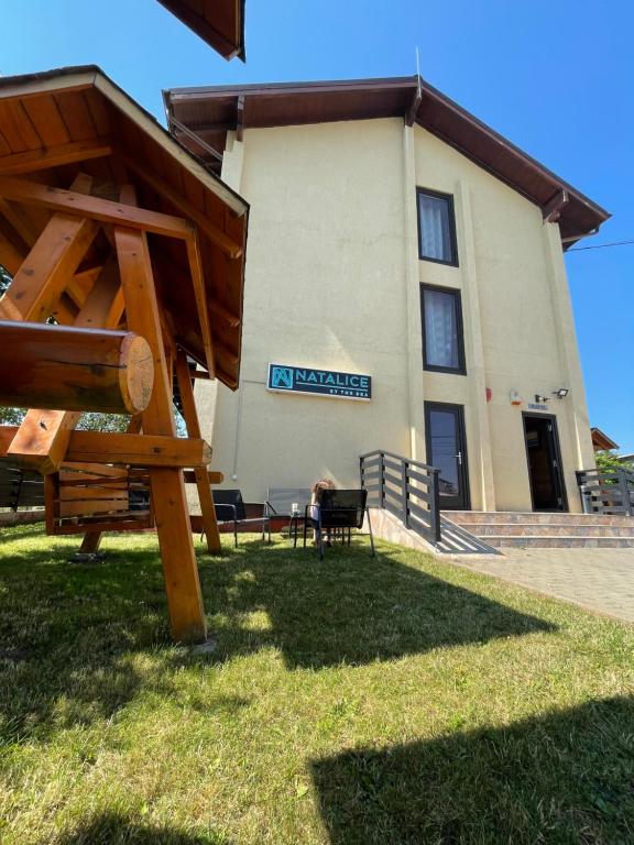 un bâtiment avec une personne assise sur un banc dans l'herbe dans l'établissement Natalice By The Sea, à Costinesti