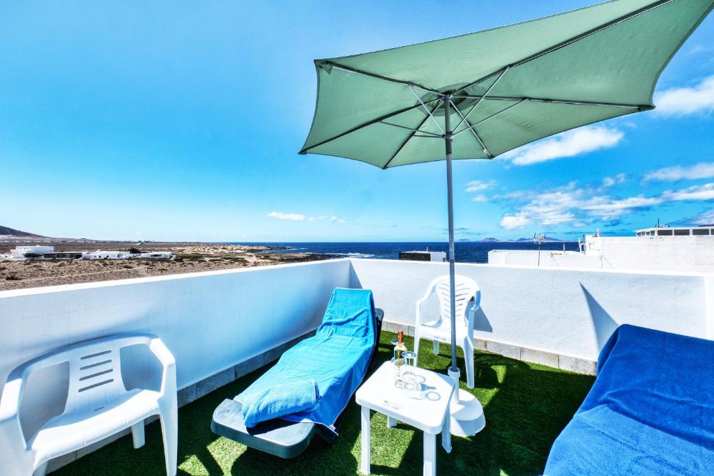 un patio con due sedie e un ombrellone di Karma Famara 1 a 25m del mar a Famara