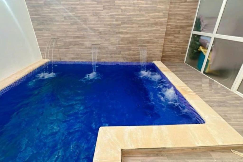 a large blue pool in a bathroom with a shower at Chez Sarah in Beni Khiar