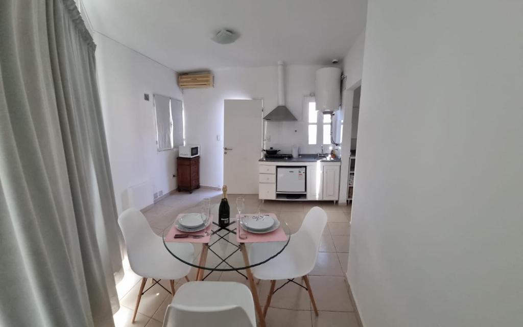 Un comedor con una mesa de cristal y sillas blancas. en Departamento centro ciudad, en Mendoza