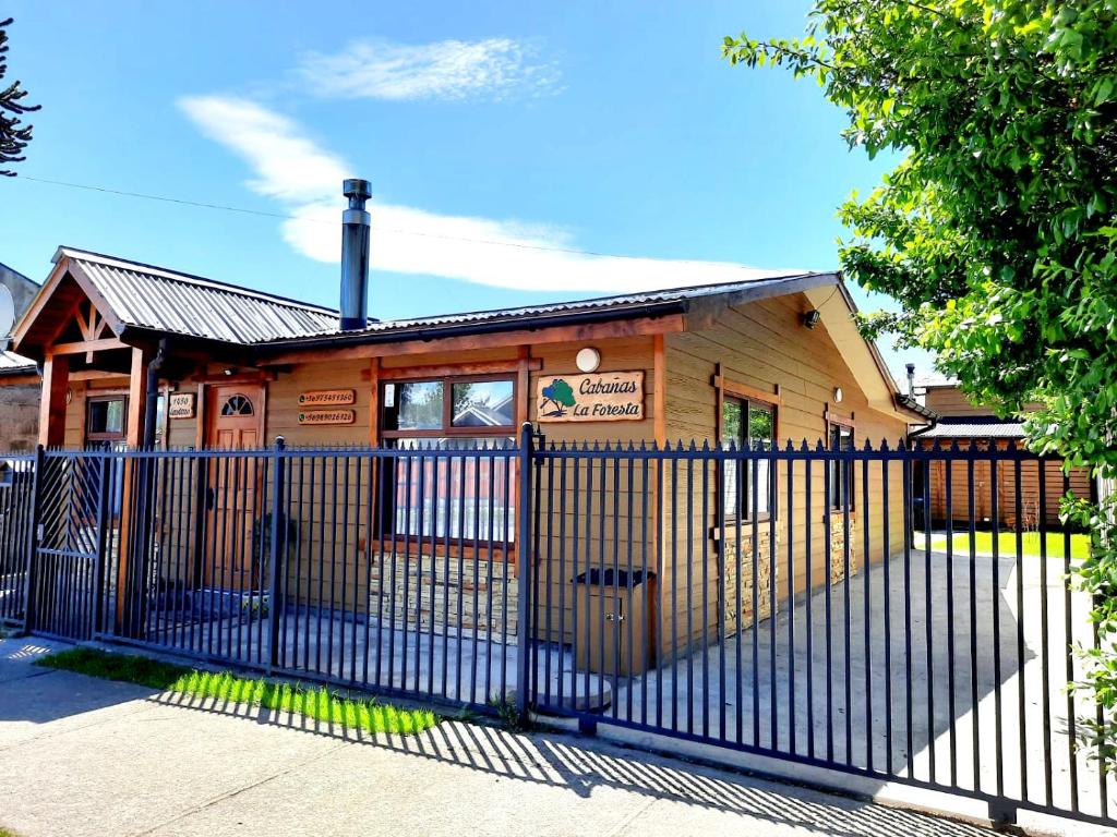 a building with a fence in front of it at Cabaña La Foresta in Coihaique