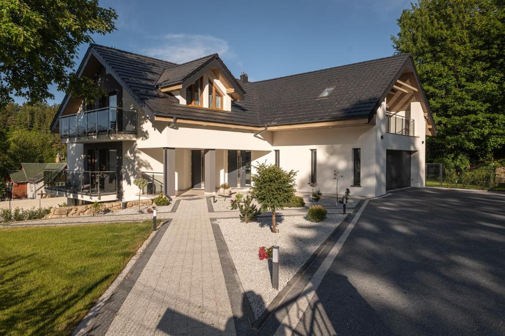 una casa blanca con techo negro en Apartamenty Aspen, en Karpacz