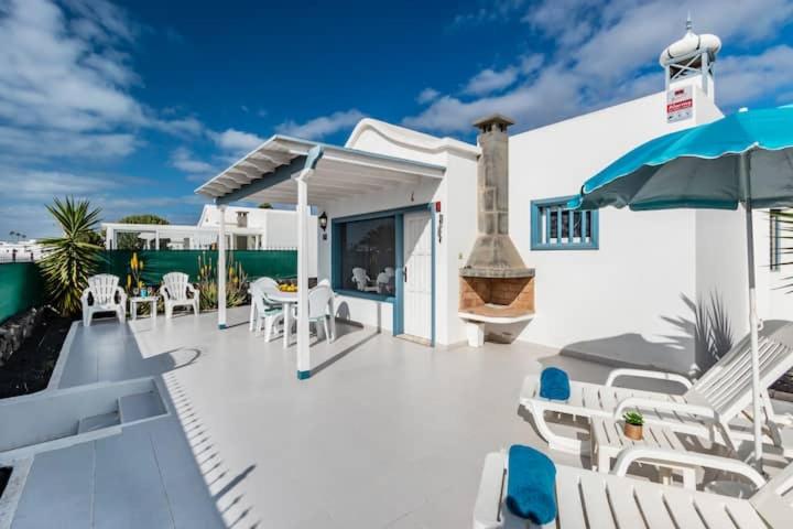 a patio with white chairs and an umbrella at Caserones 04 in Puerto del Carmen