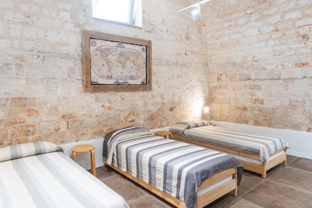 a room with two beds and a bath tub at Ostello dei Giardini di Pomona in Cisternino