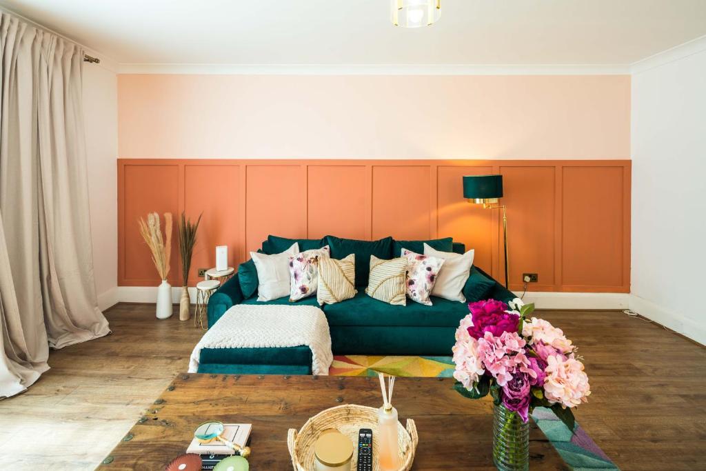 ein Wohnzimmer mit einer grünen Couch und Blumen in der Unterkunft Ventilated Central 2BR Flat 5 min from Station in London