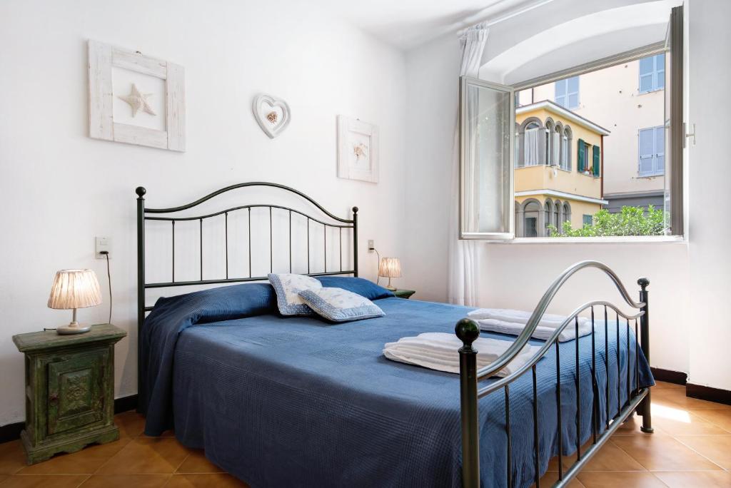 a bedroom with a bed with blue sheets and a window at Oceane Paradise- Charlot in Levanto