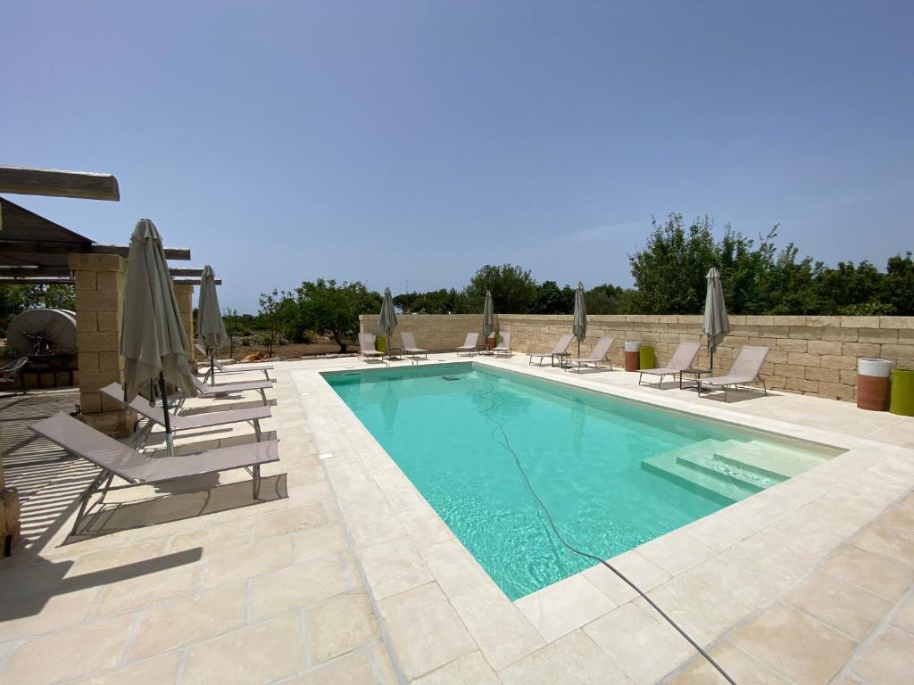 a swimming pool with chairs and umbrellas at Tenuta Palmira agriturismo in Salve