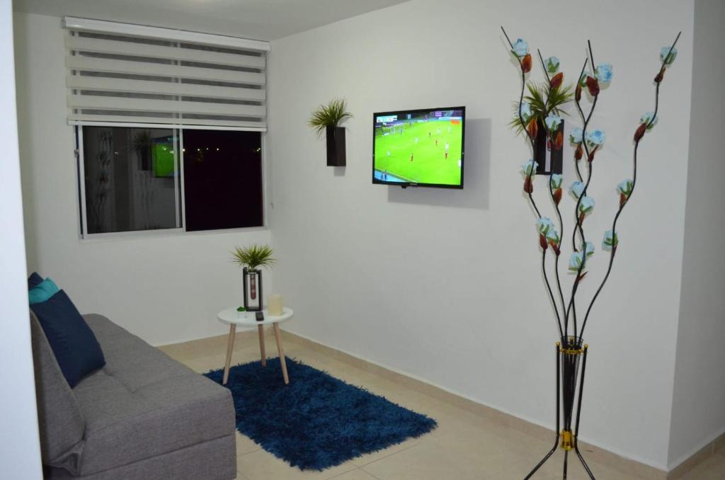 a living room with a couch and a tv on a wall at Apartamentos con Piscina cerca a Parque del Cafe in Montenegro