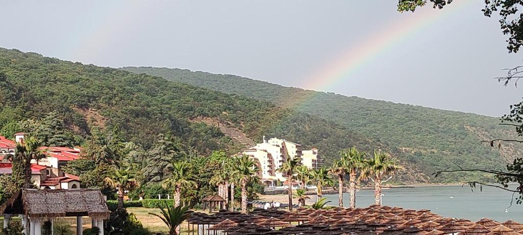 a rainbow over a mountain with a town and a river at Апартамент на метри от плажа in Sveti Vlas