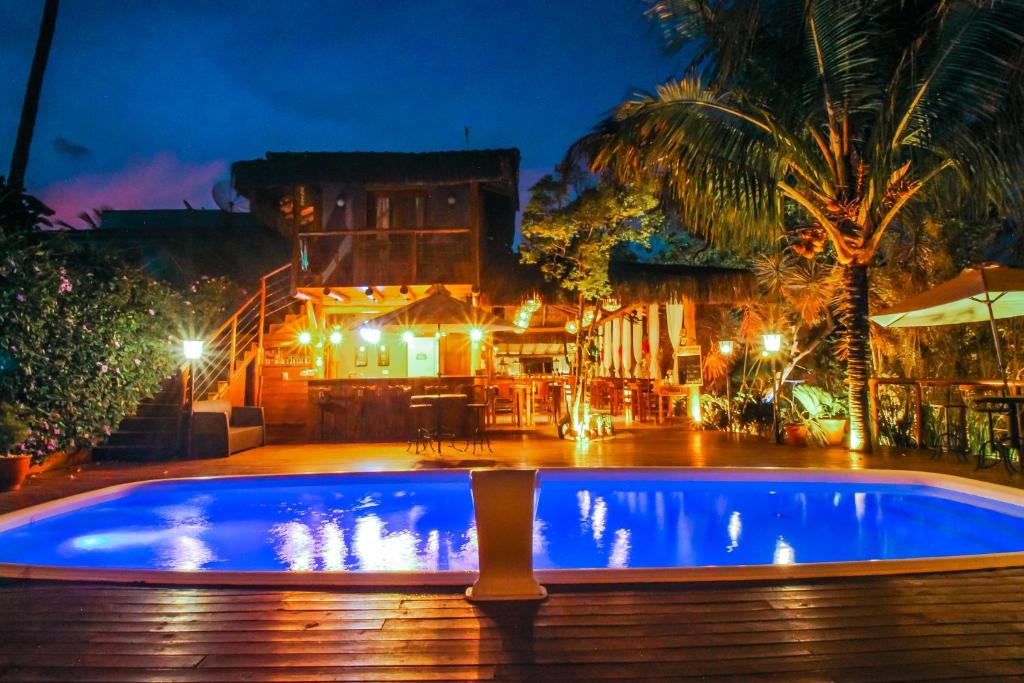 a swimming pool in front of a house at night at Pousada de Charme Emirados in Ilhabela