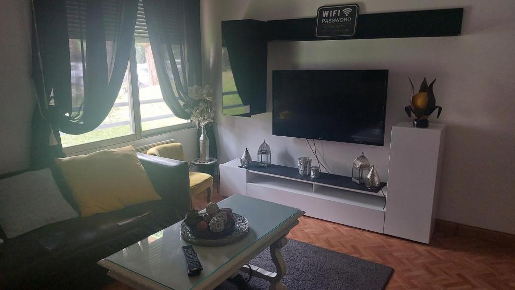 Chez mimi في تولوز: غرفة معيشة مع أريكة وتلفزيون بشاشة مسطحة