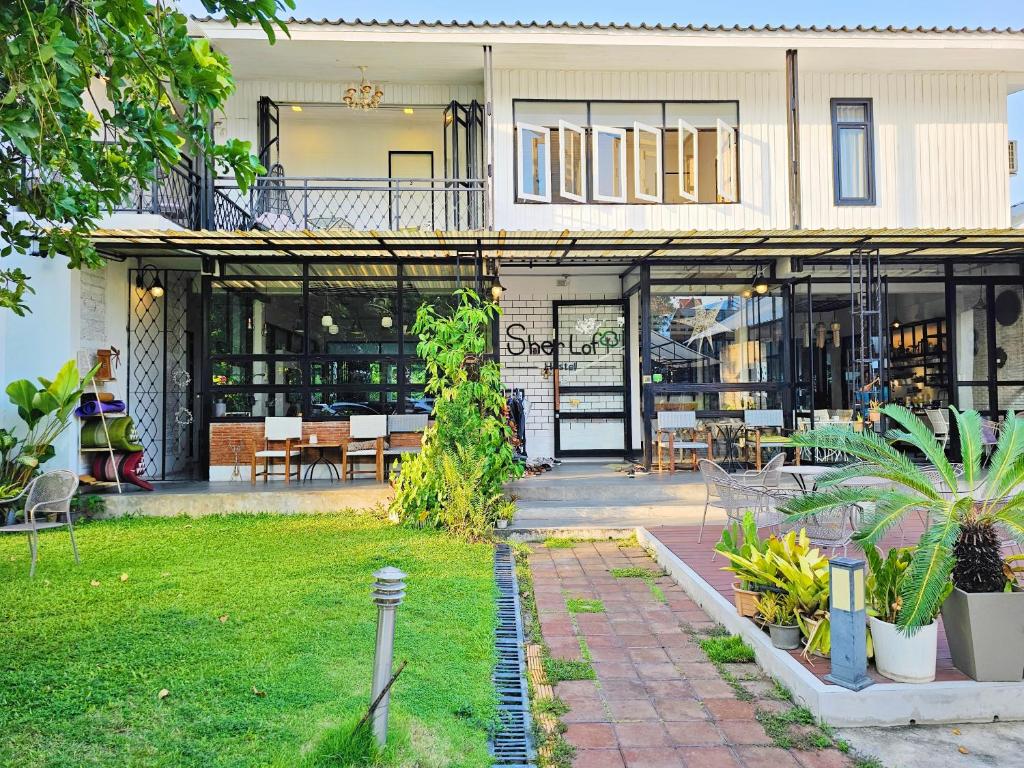 a house with a patio and a yard with plants at Sherloft Home & Hostel in Chiang Mai