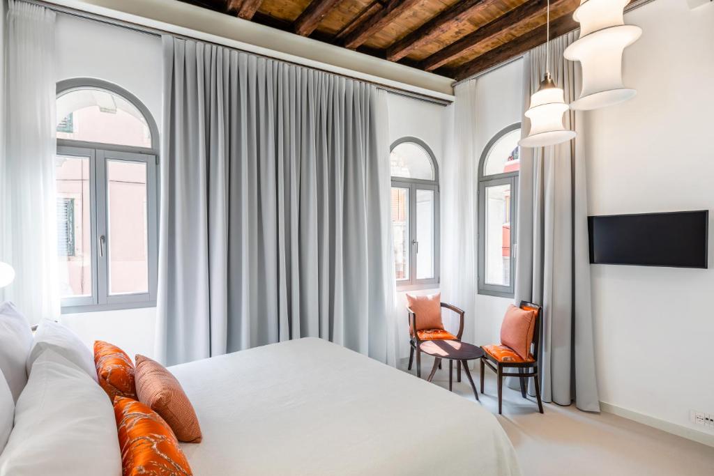1 dormitorio con 1 cama, 2 sillas y ventanas en Palazzo Basilisco Luxury Suite, en Rovinj