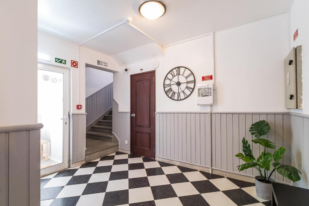 a hallway with a clock on the wall and a checkered floor at Guesthouse Aljezur Center in Aljezur