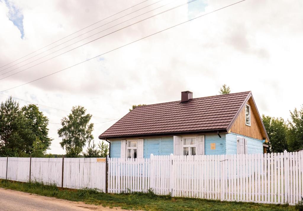 una casa azul detrás de una valla blanca en Siedlisko Niezapominajka - domek z basenem i balią, 