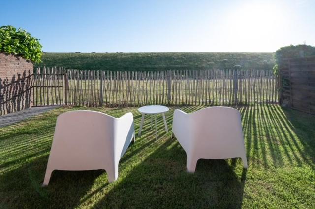 two chairs and a table in a yard with a fence at Dyk hûs in Moddergat