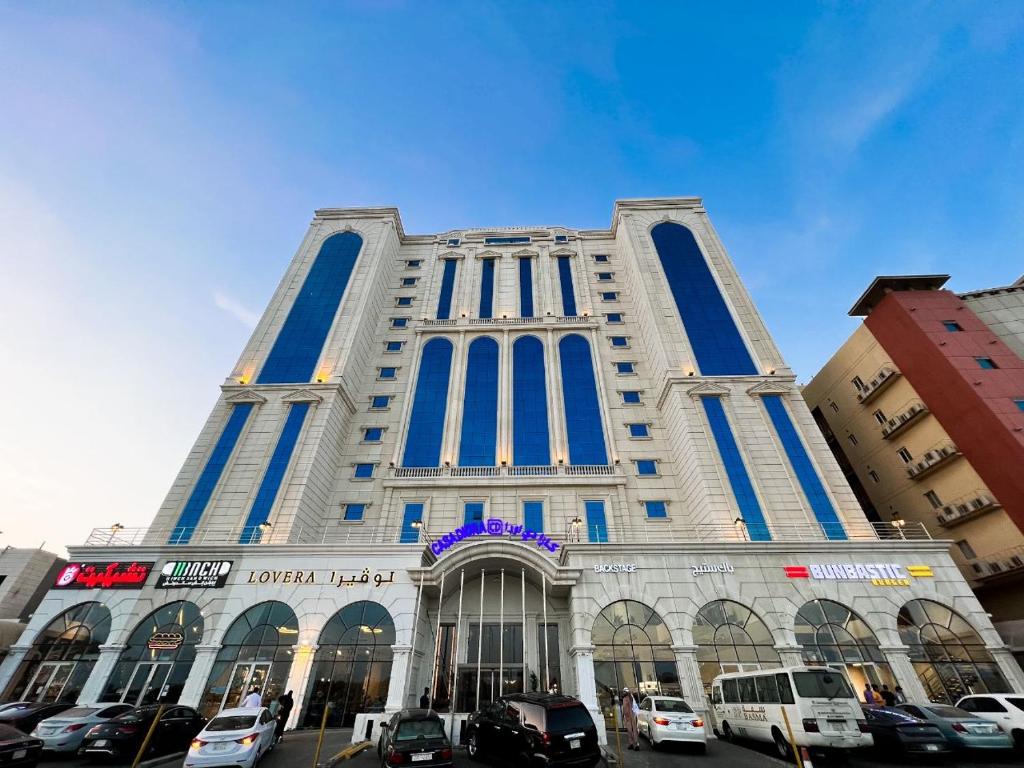 un edificio alto con coches estacionados frente a él en Casa Diora Hotel Jeddah en Yeda