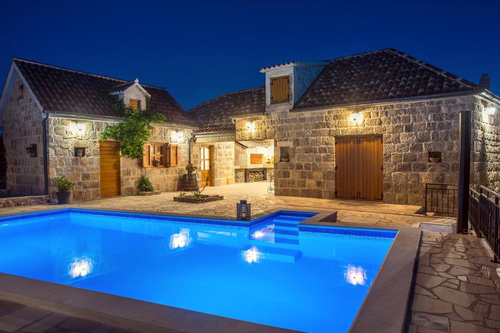 a swimming pool in front of a house at night at VIP Luxury villa with a heated pool and jacuzzi-Granny's Gold in Lovreć