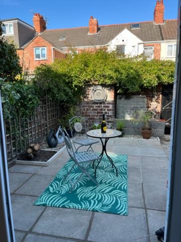 a table with a bottle of wine sitting on a patio at Newton Road Home A small cosy comfortable 2 bedroom terrace house in Great Meols