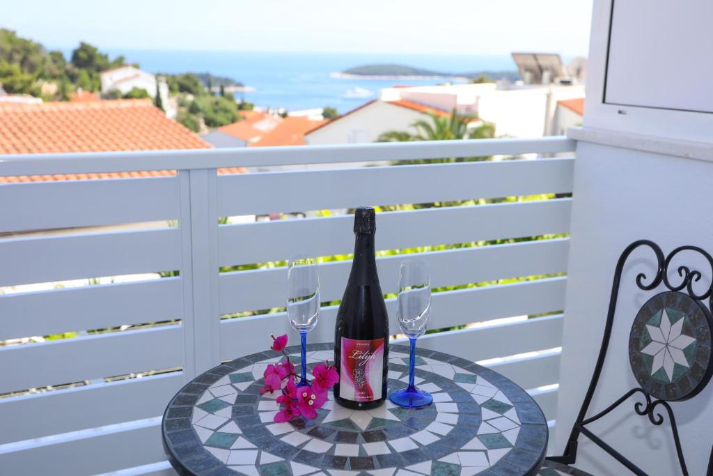 Una botella de vino y dos copas en una mesa en un balcón. en Stella Maris - Rooms & Apartment, Hvar en Hvar