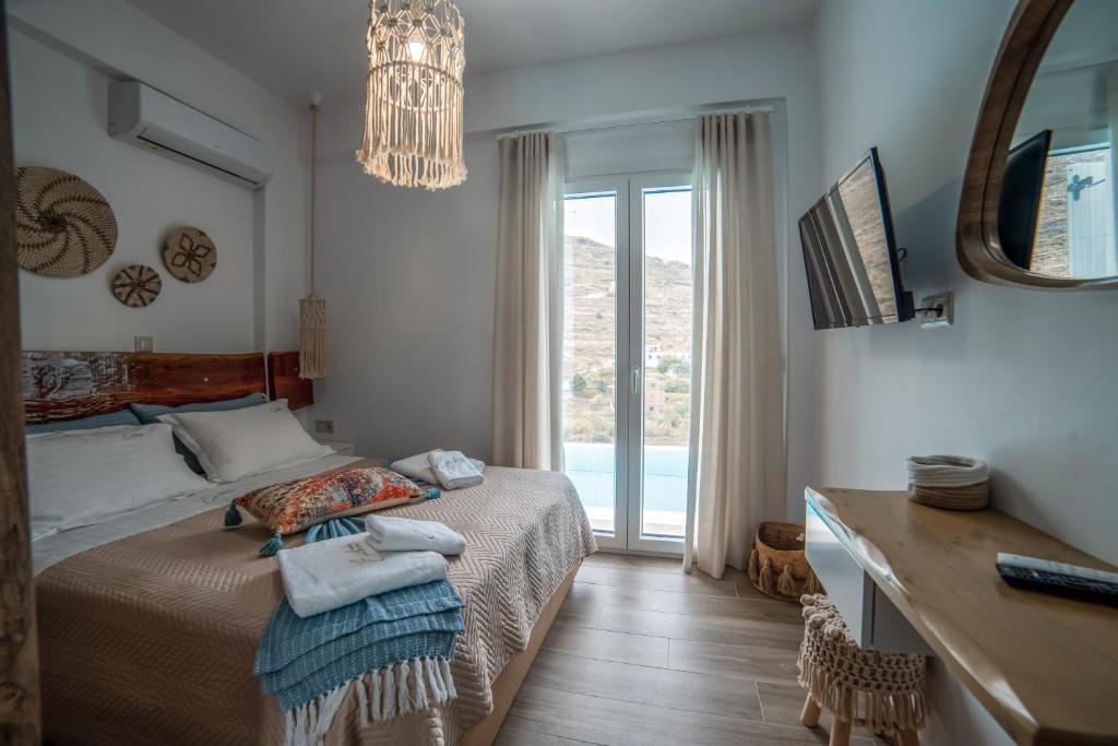 um quarto com uma cama, uma secretária e uma janela em Epithea Suites Kythnos 1 με ιδιωτική πισίνα em Kythnos