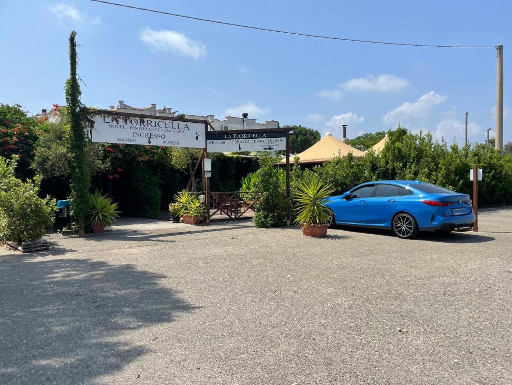 un coche azul estacionado en un estacionamiento en Hotel La Torricella, en Capalbio