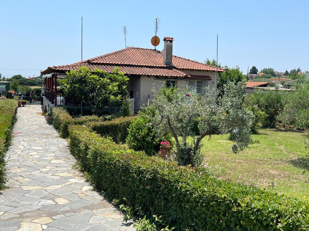 a house with a row of hedges in a yard at Vila Katerina Anna in Nea Kalikratia