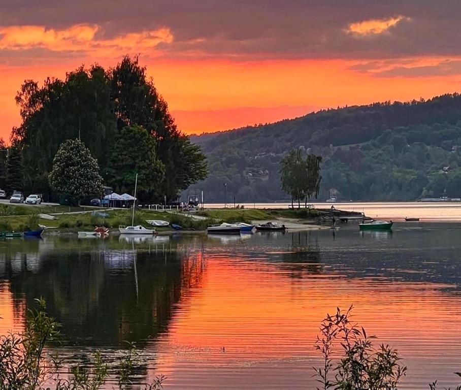 a sunset over a lake with boats in the water at Apartament Lux SunRise in Żywiec