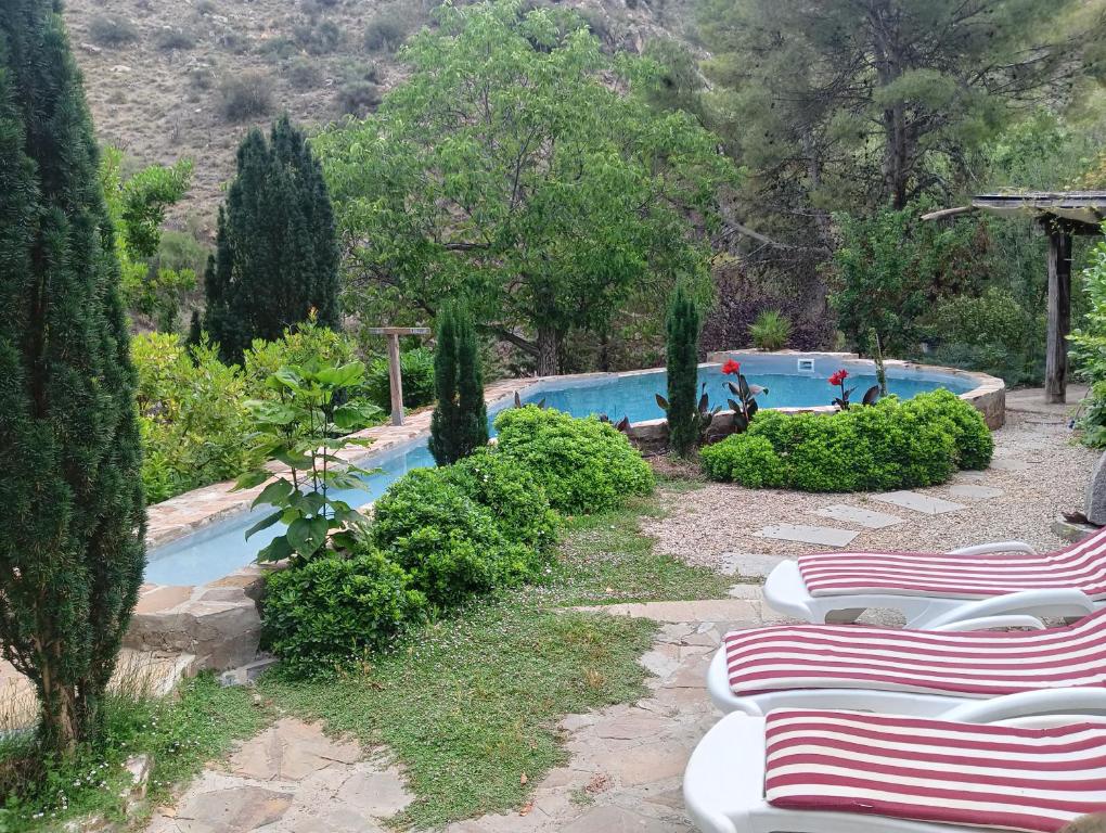 a group of lounge chairs next to a swimming pool at La Casita con piscina privada de tres dormitorios in Torres